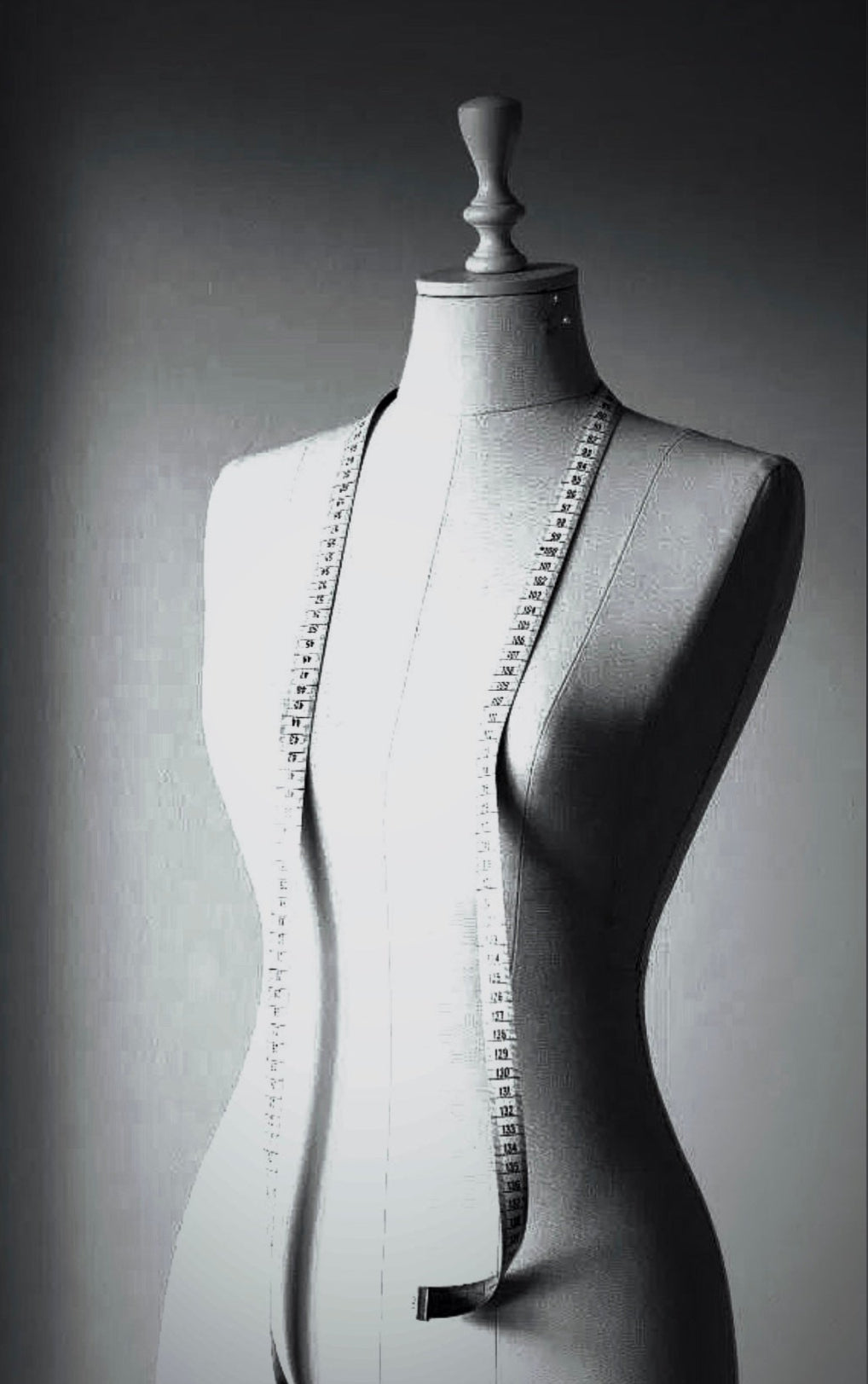 Mannequin torso with a measuring tape draped over it on a dark background